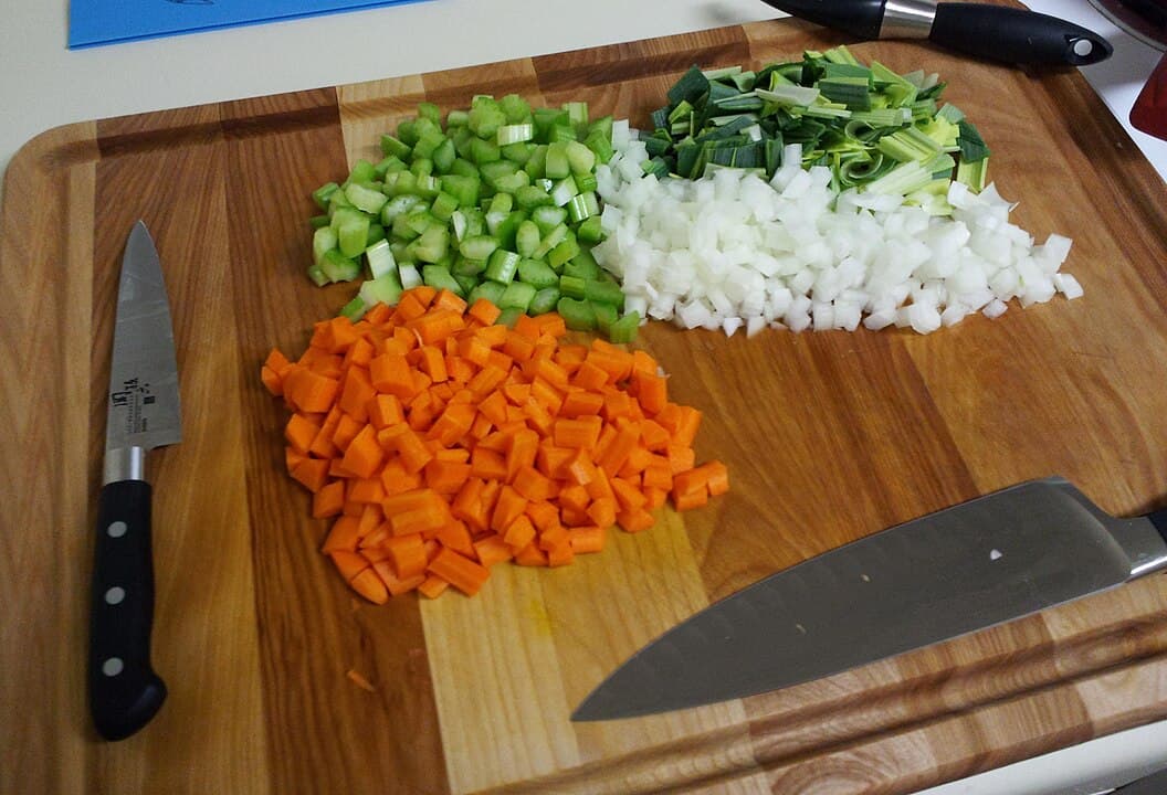 des légumes coupés en mirepoix sur une planche à découper