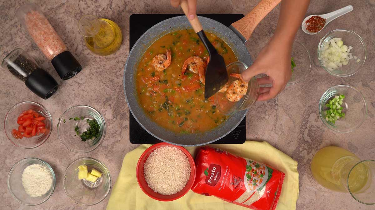 L'ajout des crevettes préalablement sautées dans la sauce épaisse et parfumée.