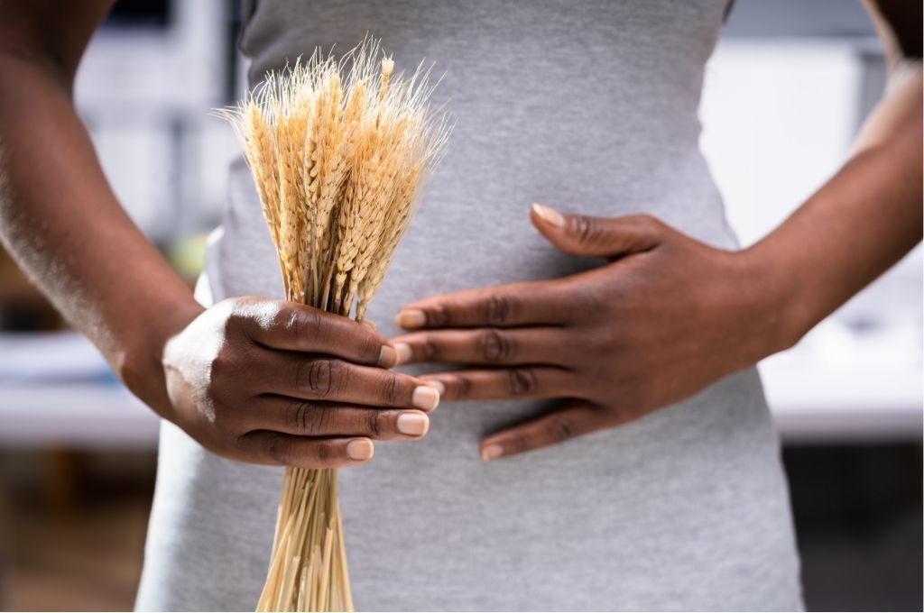 Une personne tient un bouquet de blé et pose sa main sur son ventre