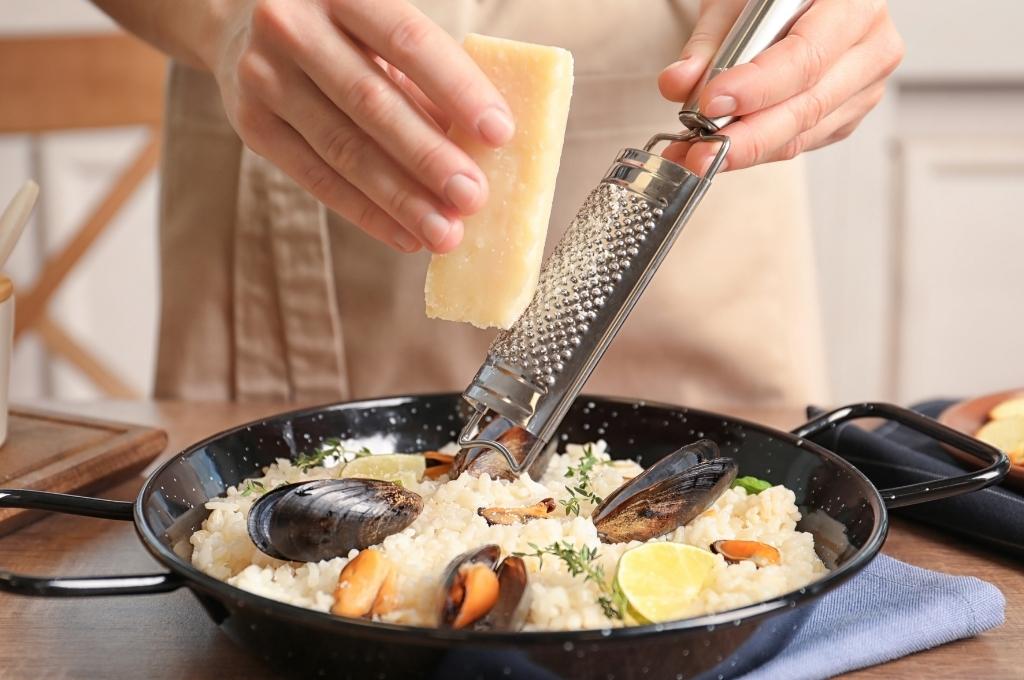 un cuisinier trappe le parmesan sur un plat de risotto