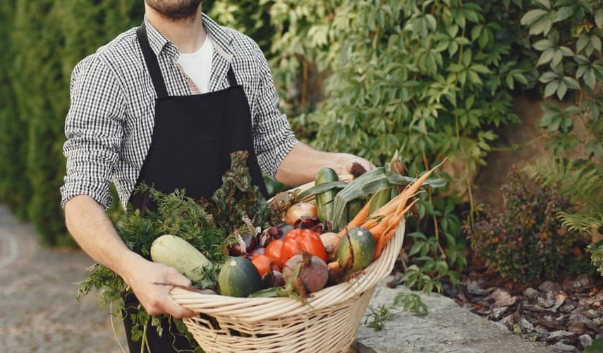 un fermier qui porte un panier de légumes variés