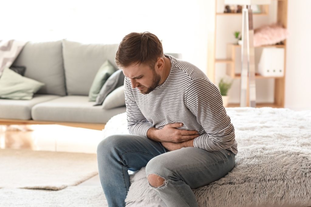 Homme souffrant de maux de ventre, potentiellement liés à un apport inadéquat en nutriments comme l'acide folique