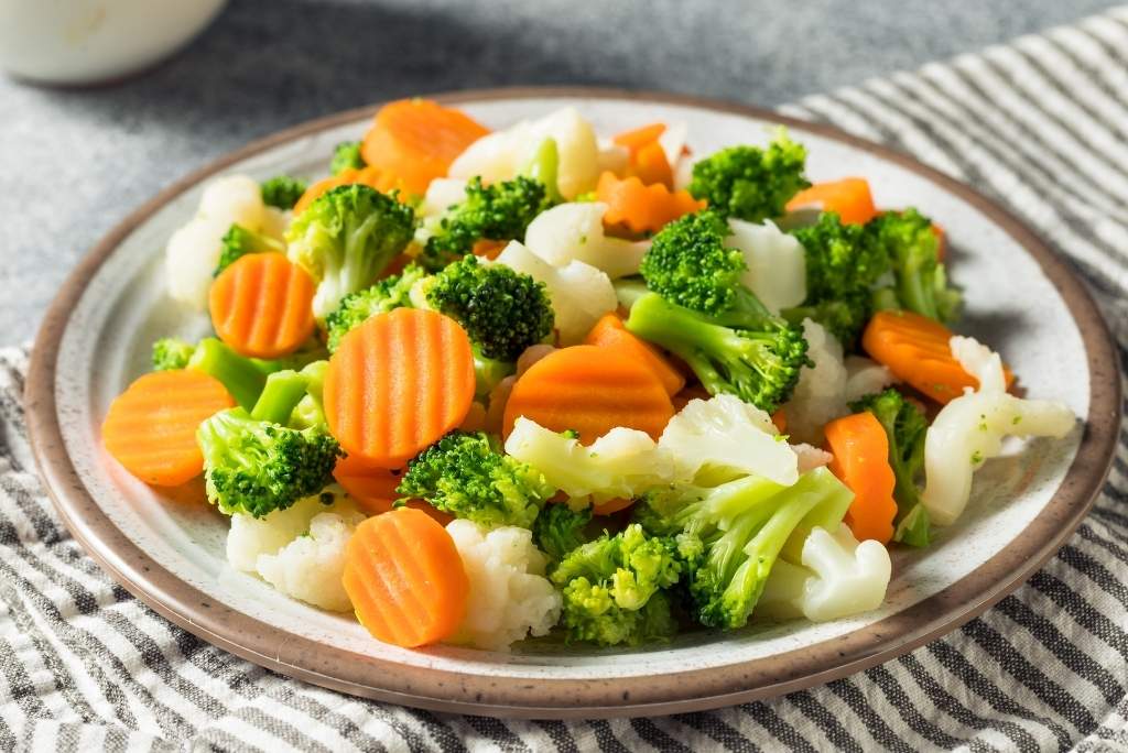 استلهموا وصفات بسيطة وشهية طبق خضار على الطريقة الآسيوية، يتضمن زهرات البروكلي والقرنبيط وشرائح الجزر، ويقدم على طبق أبيض.