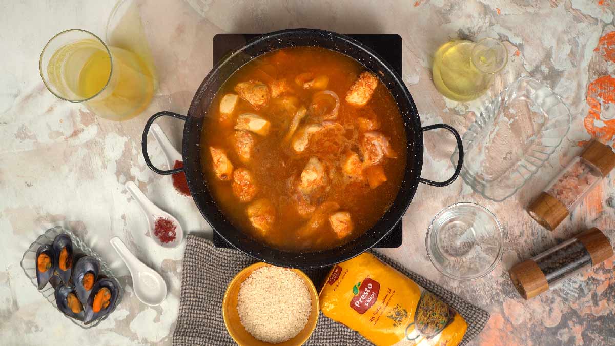 البايلا تُطهى على نار هادئة، حيث ينضج الأرز والدجاج والمأكولات البحرية في المرق. 