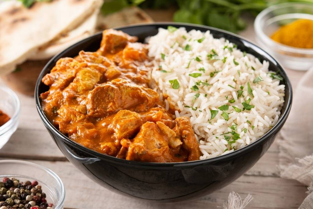 طبق من الأرز الأبيض وكاري الدجاج يقدم في وعاء أسود.