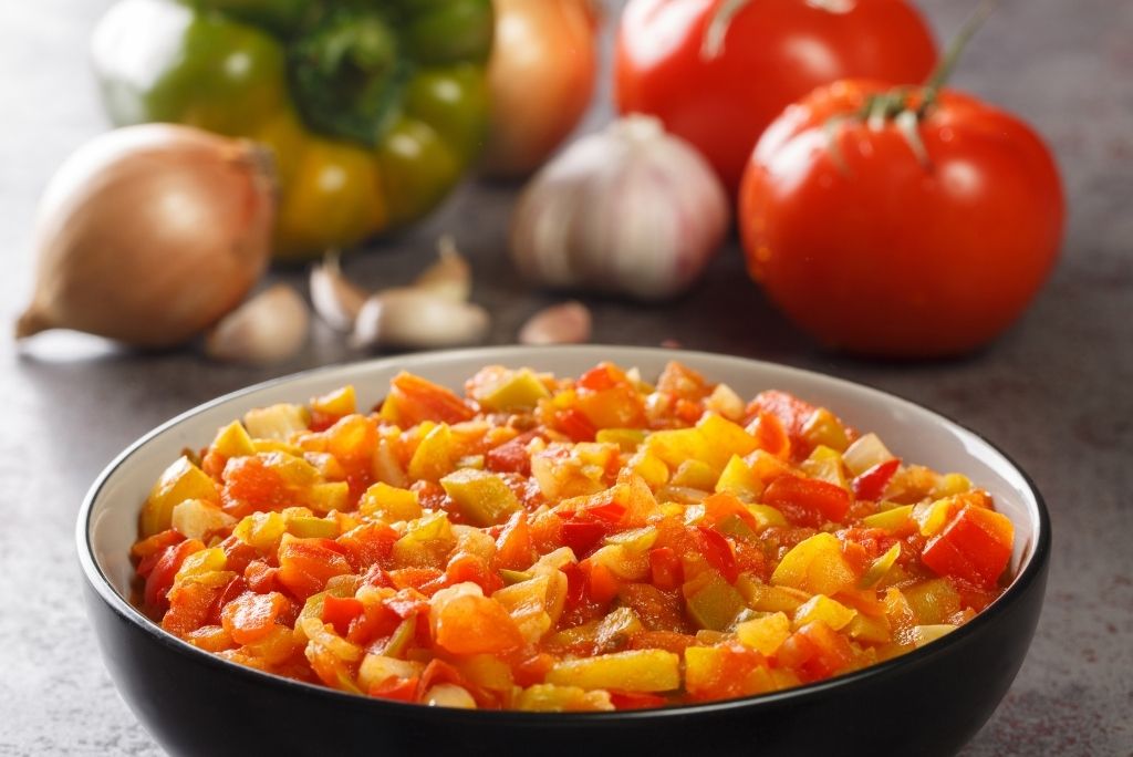 الخضروات توفر الفيتامينات والمعادن ومضادات الأكسدة وعاء يحتوي على خضروات مفرومة ومطهوة مع خضروات طازجة في الخلفية.