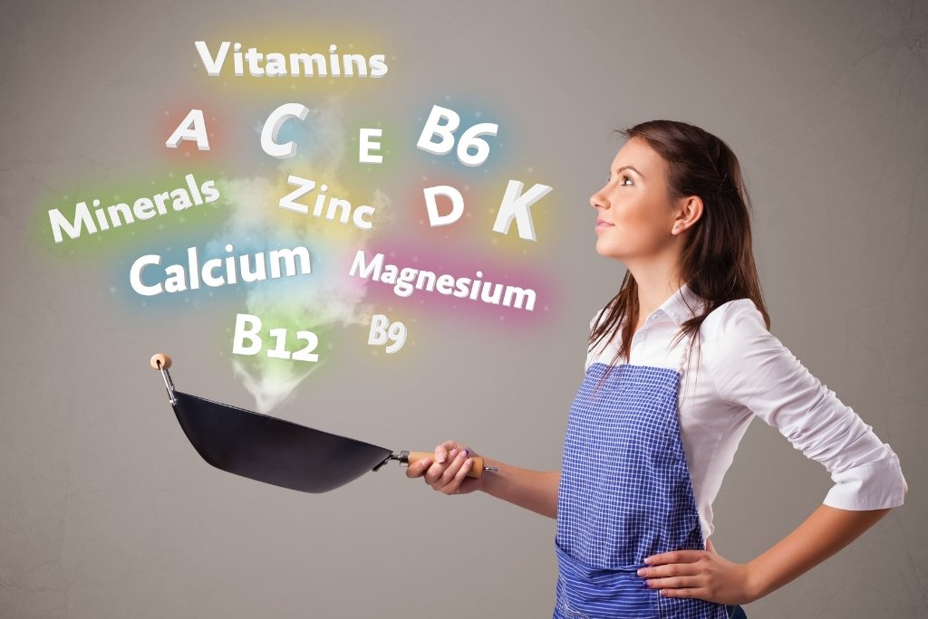 السيلينيوم امرأة ترتدي مئزرًا تحمل مقلاة تتصاعد منها كلمات مضيئة تمثل الفيتامينات والمعادن.