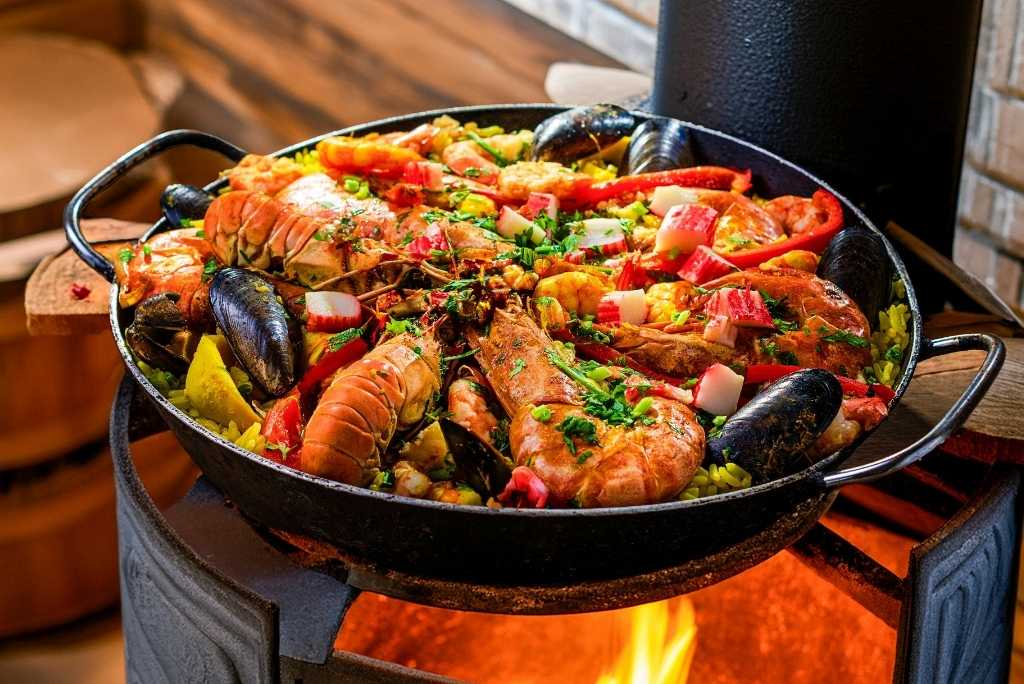 طبق باييلا بالمأكولات البحرية مزين بالجمبري وبلح البحر وشرائح الليمون.