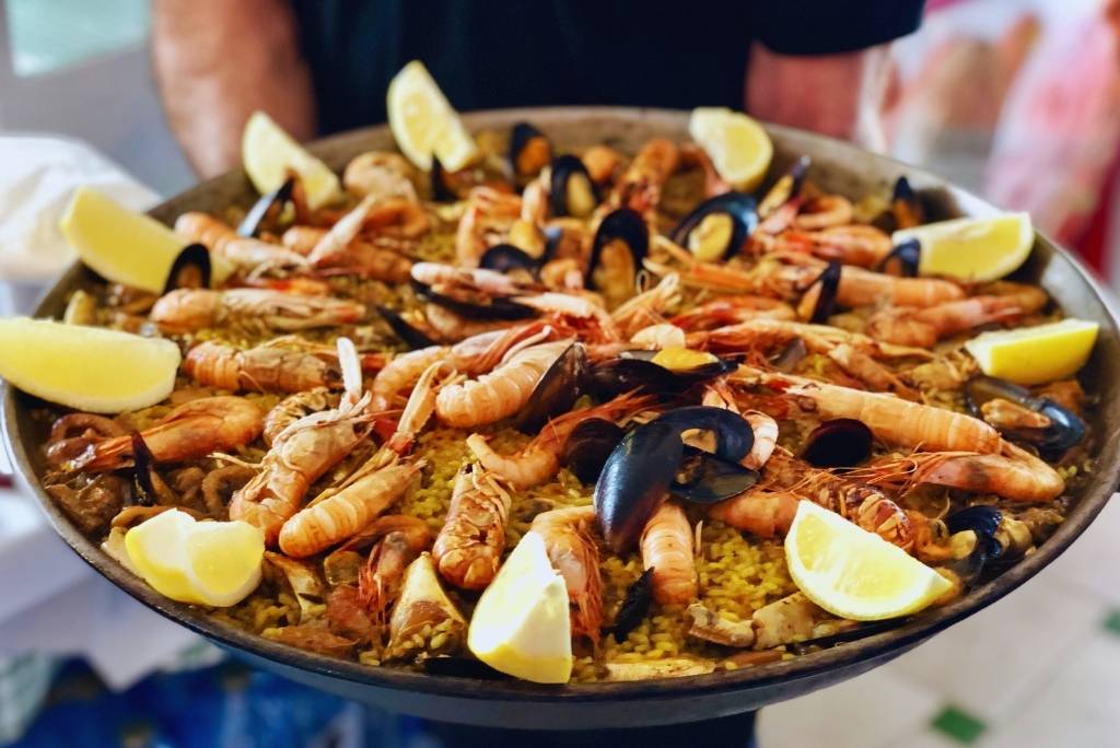 بايلا بالمأكولات البحرية مزينة بالقمرون وبلح البحر واللانجوستين، تطهى فوق لهب.