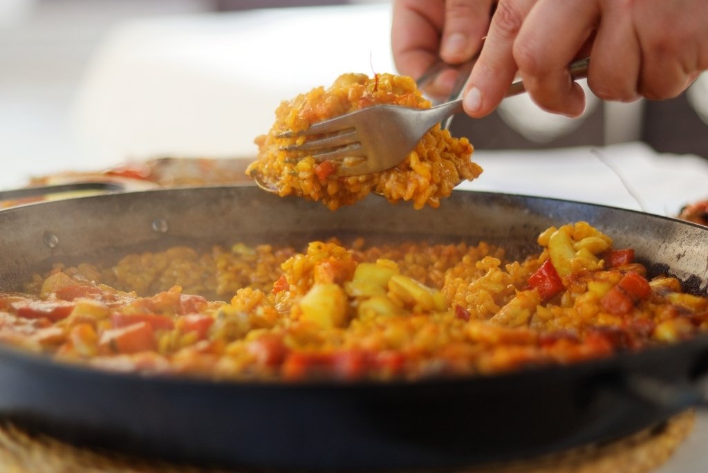 لقطة مقربة لملعقة ترفع حصة من البايلا مباشرة من المقلاة.