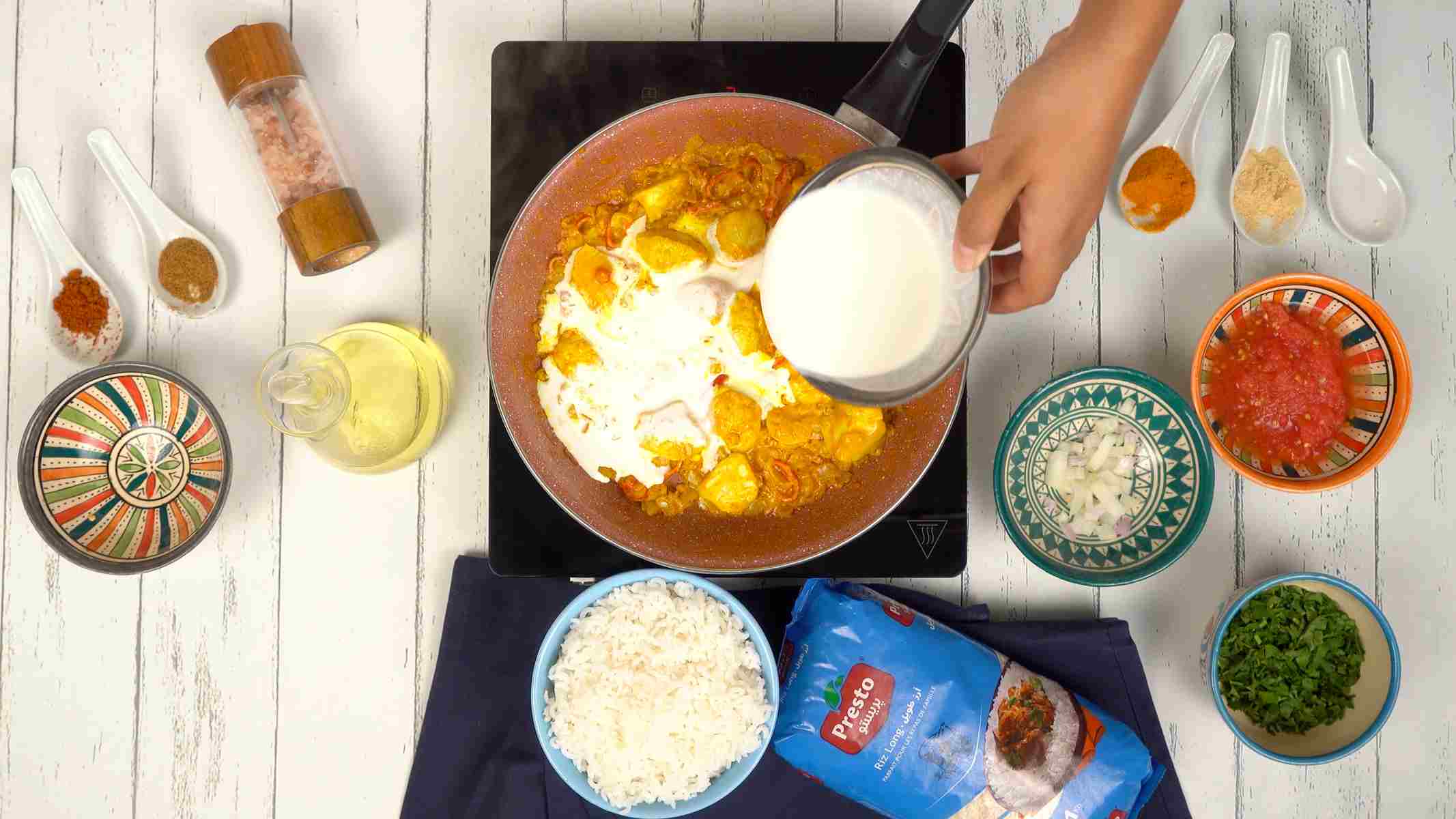 تحضير صلصة التيكا ماسالا شخص يسكب الحليب أو الكريمة في المقلاة مع الدجاج والصلصة لتحضير صلصة الماسالا.