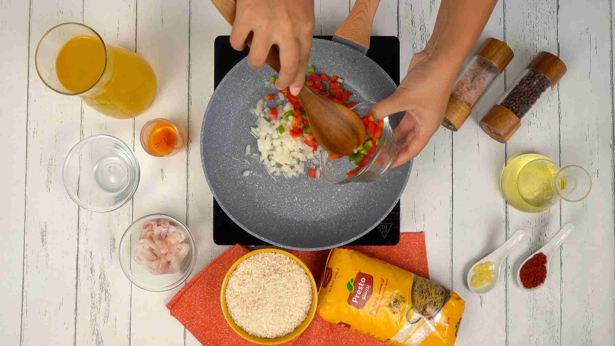 تشويح الخضار شخص يضيف مكعبات من البصل والفلفل إلى المقلاة لتشويحها.