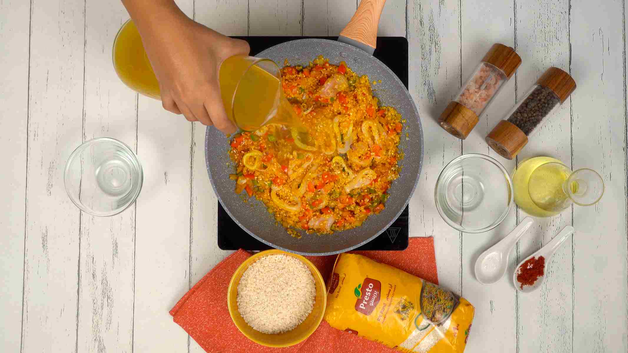 الطهي بمرق السمك شخص يسكب المرق في المقلاة لطهي الأرز.