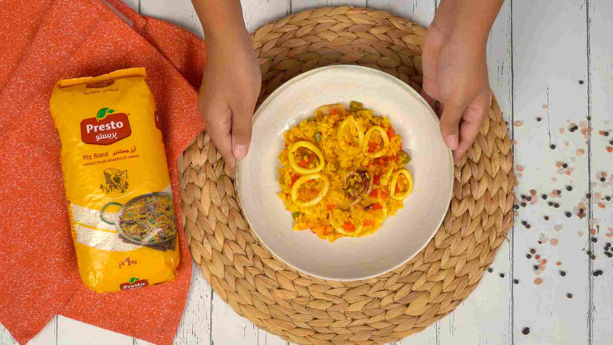 التقديم والتذوق طبق من الأرز بالكالمار والخضار يُقدّم في صحن أبيض.