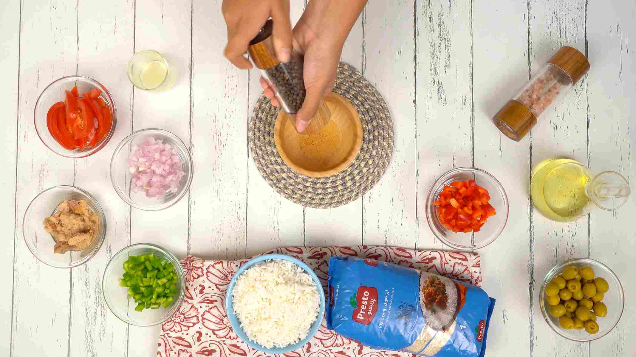Préparer la sauce Une personne prépare une vinaigrette en moulant du poivre dans un petit bol en bois.