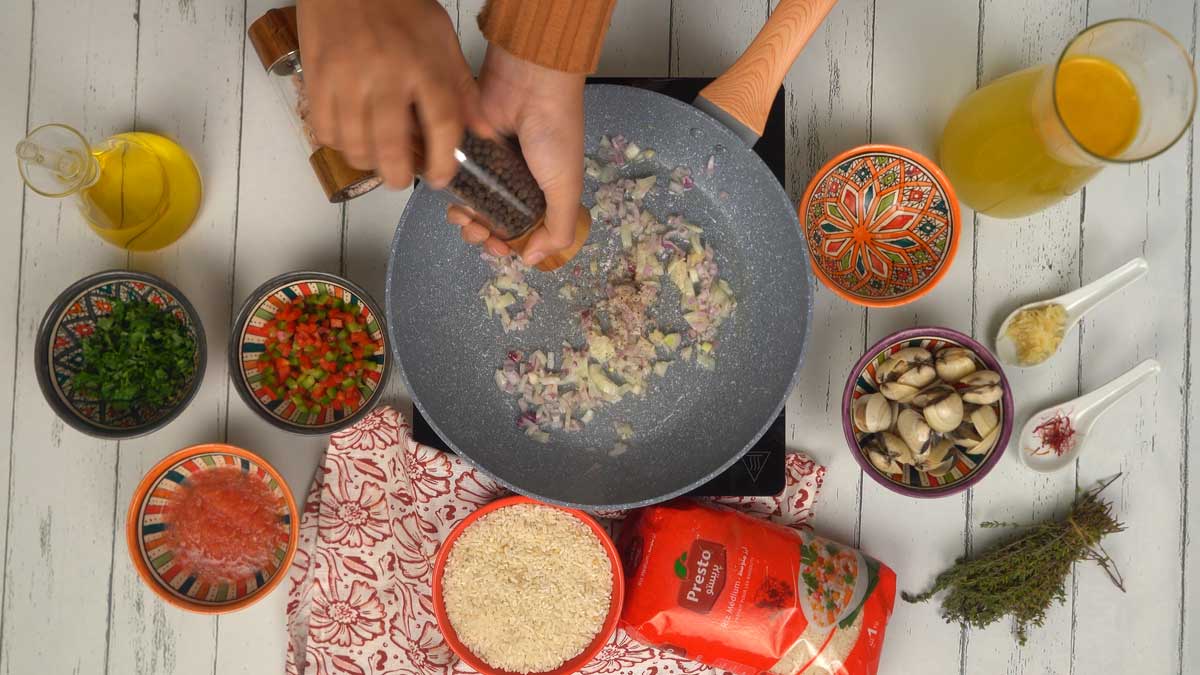 La cuisson commence par faire suer les oignons rouges émincés avec de l'ail et du poivre moulu dans une poêle bien chaude.