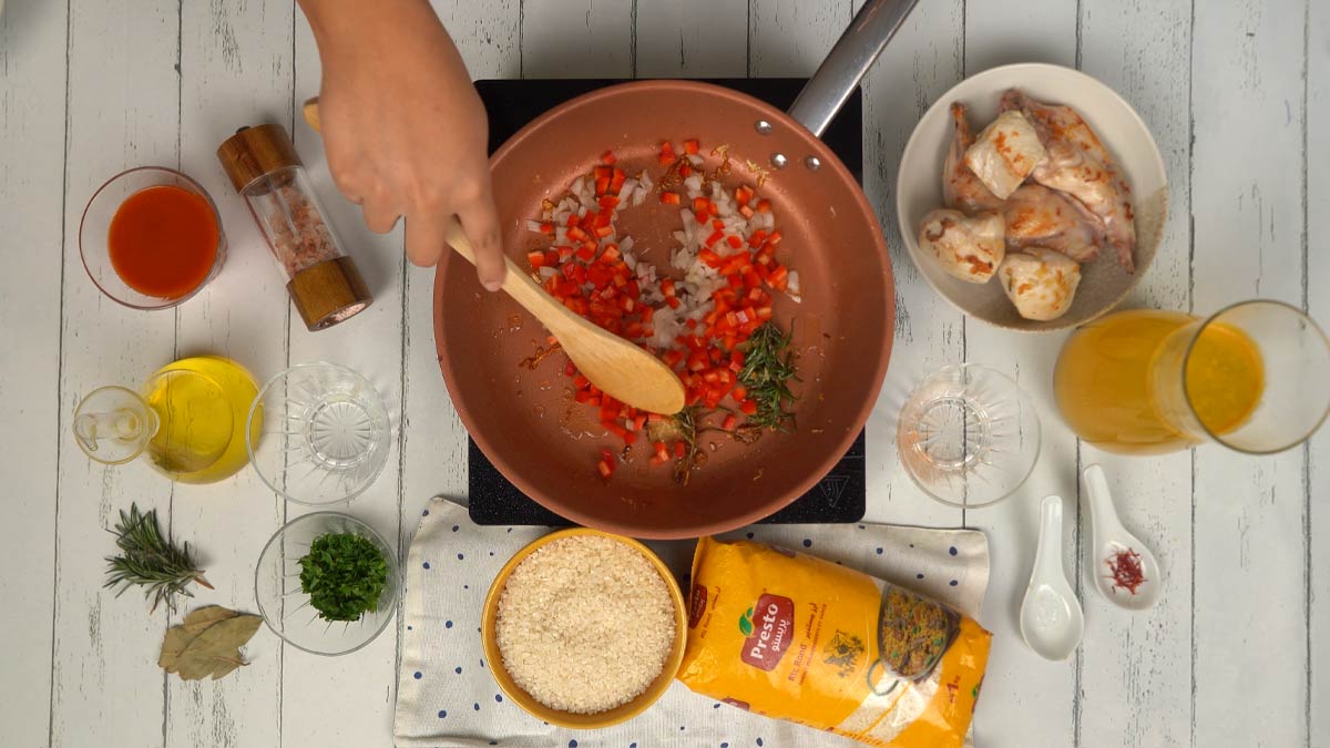 Préparer la base de légumes On ajoute ensuite des oignons et des poivrons rouges coupés en dés pour faire revenir les légumes avec la viande.