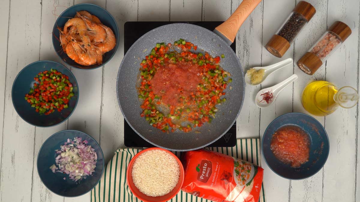 يتم تشويح مكعبات الفلفل ثم تُضاف الطماطم المبشورة لتحضير سوفريتو غني بالنكهة.