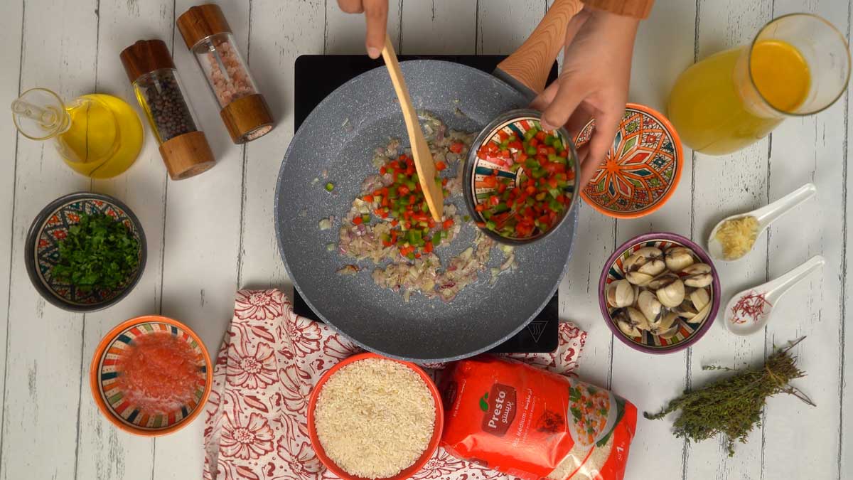 Les dés de poivrons rouges et verts sont incorporés aux oignons pour être saisis.