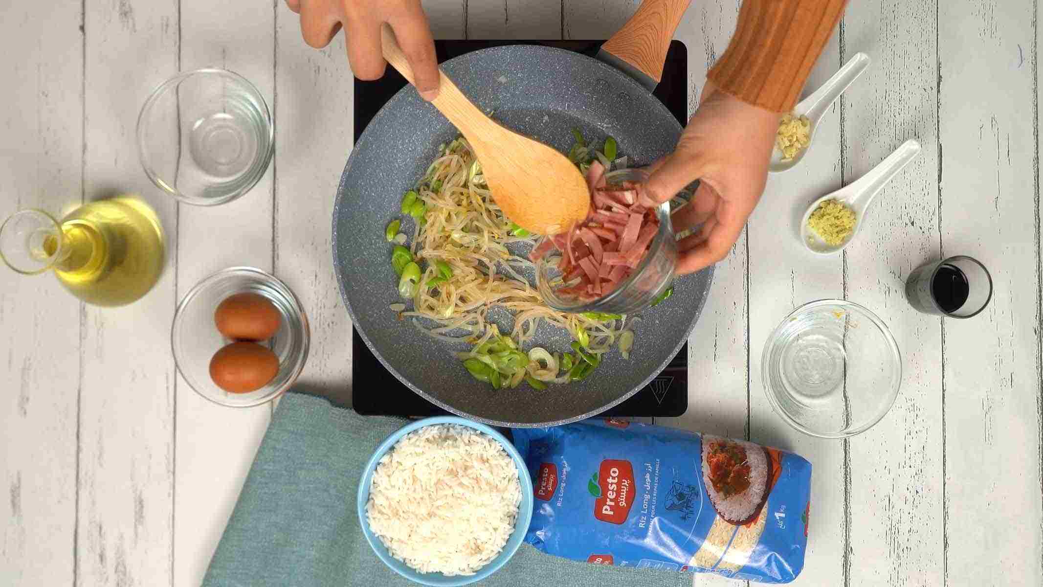 On ajoute ensuite des lanières de jambon et des germes de soja au mélange pour apporter du croquant et de la saveur.