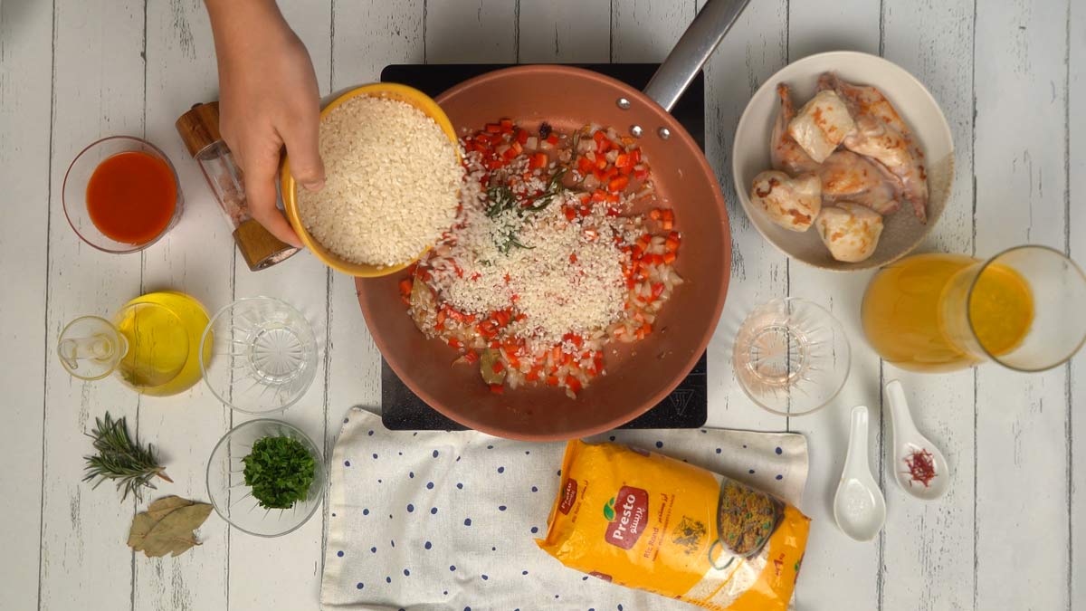 Ajouter le riz et la tomate On verse le riz rond directement dans la poêle pour qu'il s'imprègne bien du jus de cuisson et des saveurs.