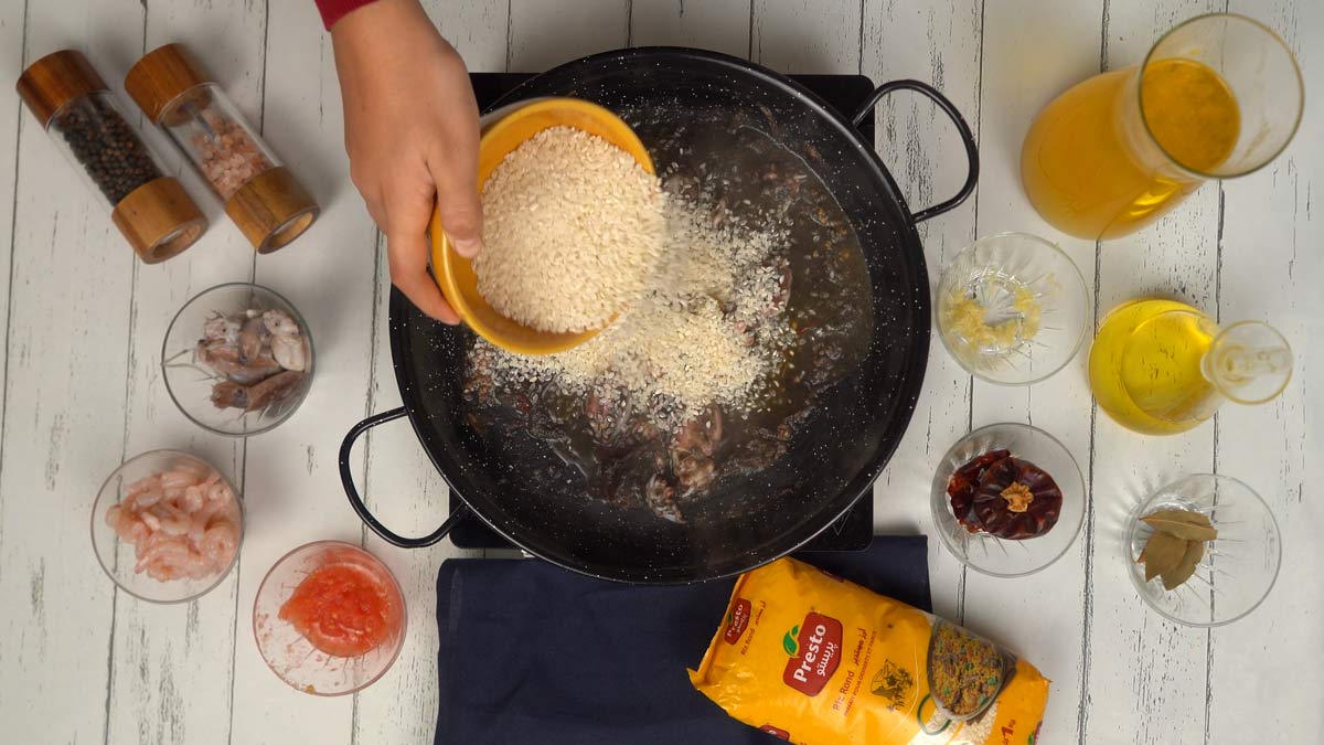 Incorporer le riz On verse le riz rond directement dans la poêle pour le faire "nacrer" (le dorer légèrement afin qu'il absorbe les saveurs).