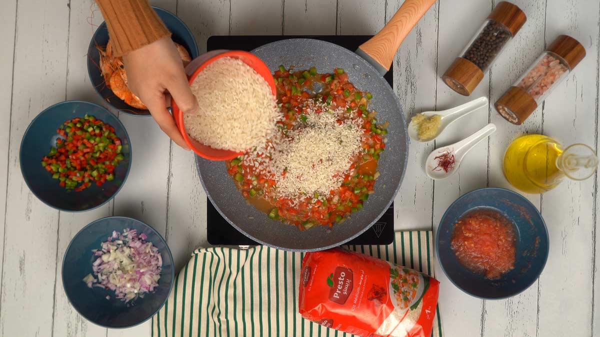 يُسكب الأرز مباشرة في المقلاة ليُخلط مع الخضار.