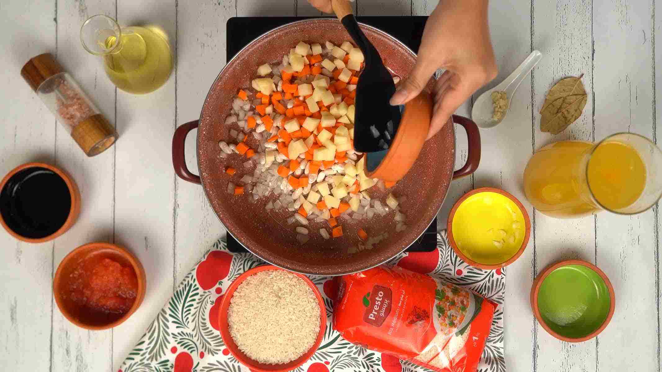 On incorpore des dés de carottes, de pommes de terre et des haricots blancs à la préparation.