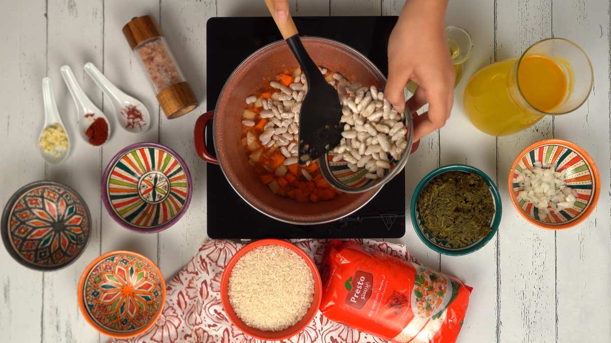 يتم إدخال الفاصوليا البيضاء ومكعّبات الجزر إلى الخليط المطهو.