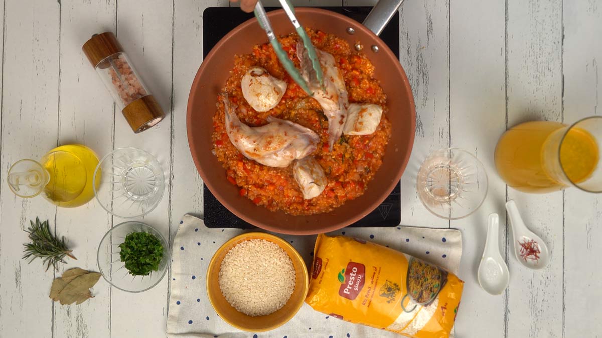 Assembler la paella On dispose harmonieusement les morceaux de viande dorés sur le lit de riz avant de poursuivre la cuisson.