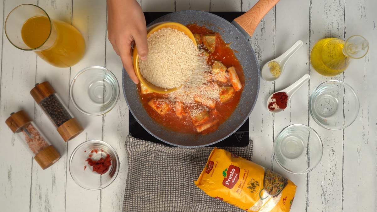 On verse le riz rond directement dans la poêle pour qu'il s'imprègne de la sauce avant d'ajouter le liquide de cuisson.