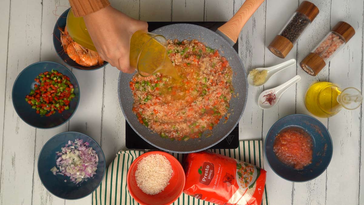 يُسكب المرق فوق خليط الأرز والخضار ليطهى بطريقة الامتصاص.