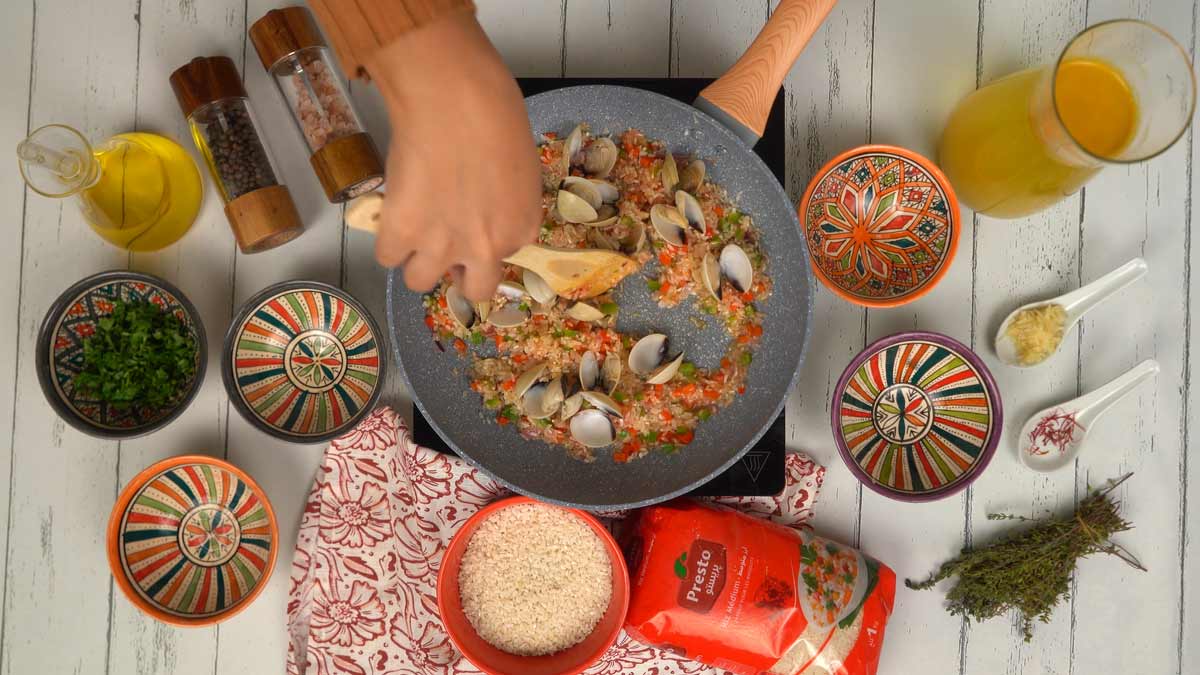 Les palourdes sont ajoutées au mélange de riz et de légumes avant le mouillage.