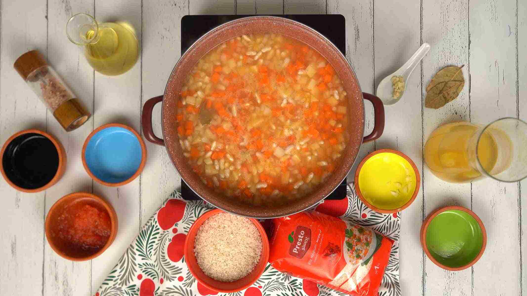 On ajoute du bouillon et on laisse mijoter l'ensemble jusqu'à ce que le riz et les légumes soient parfaitement tendres.