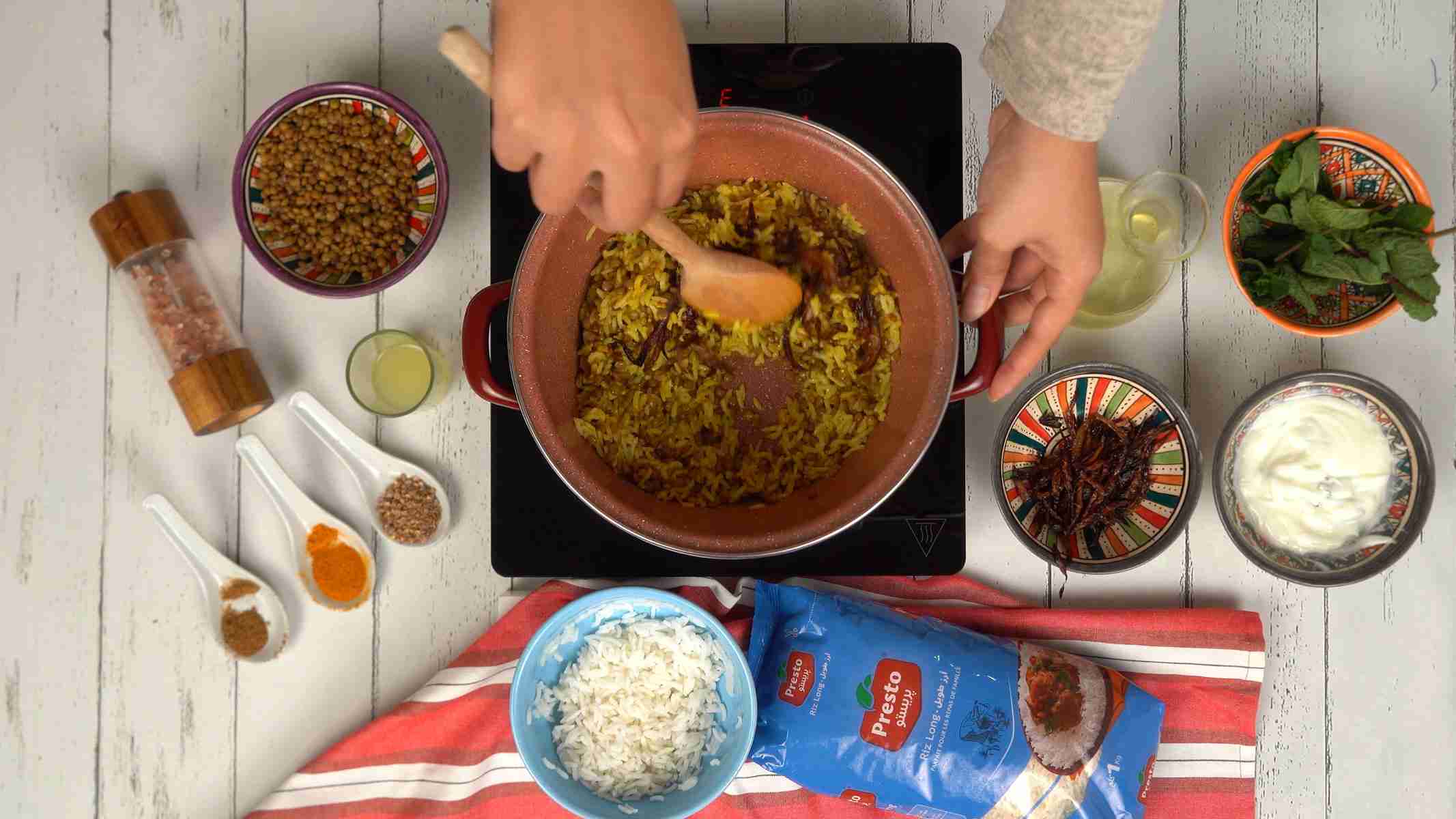 Assembler la mujaddara On mélange délicatement le riz, les lentilles et une partie des oignons frits pour bien répartir les saveurs.