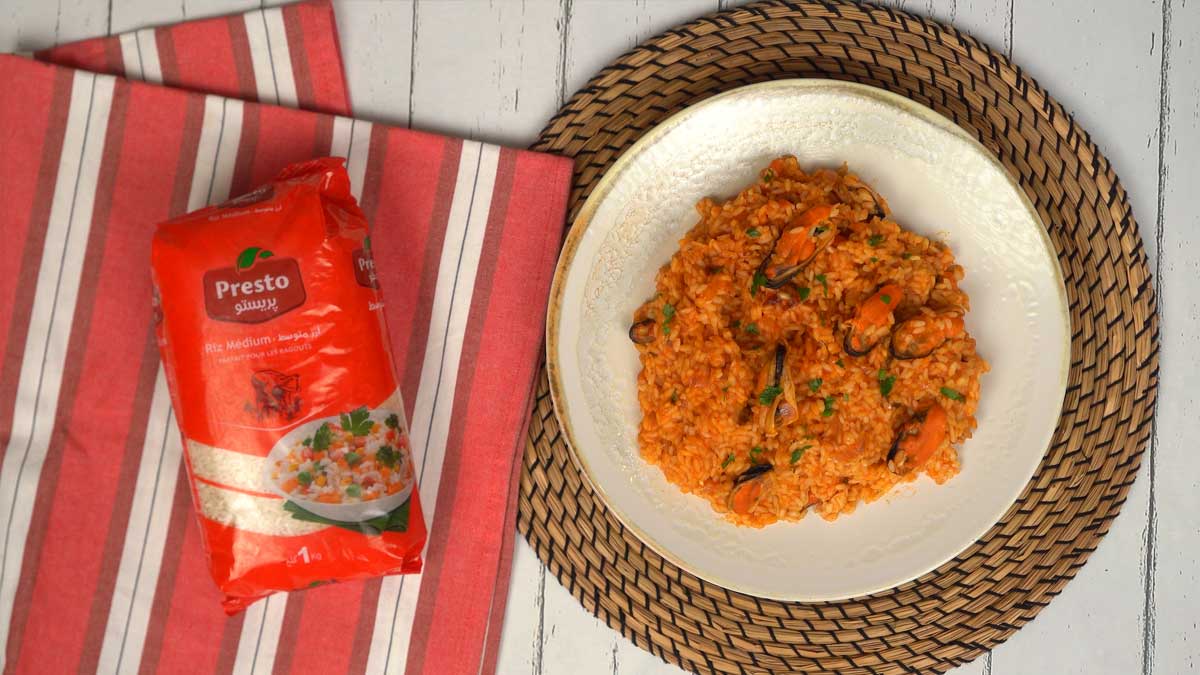 Finaliser et servir Le résultat final est un riz onctueux et orangé, généreusement garni de moules, prêt à être dégusté.