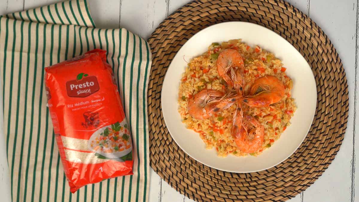 الطبق النهائي عبارة عن أرز بلون برتقالي مزين بالخضار الصغيرة والروبيان المطهو مسبقًا، ويُقدّم في طبق أبيض.