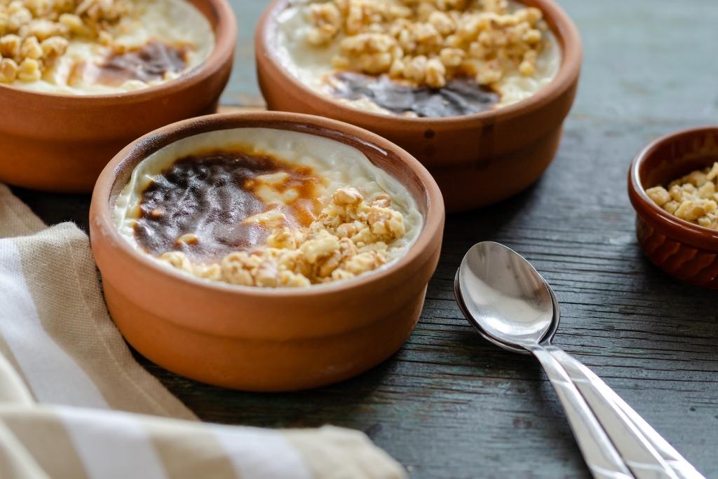ثلاثة أوعية فخارية تحتوي على أرز بالحليب بطريقة "Sütlaç" مع سطح مكرمل في الفرن ومزين بقطع البندق أو الجوز.